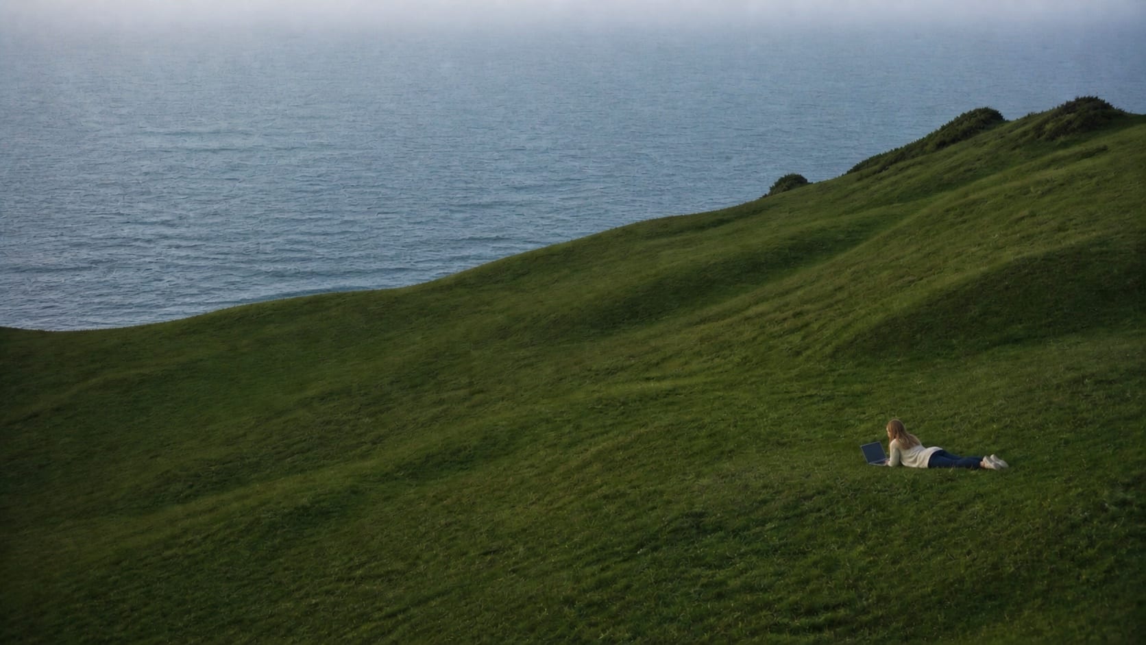 A person working on a laptop above the sea